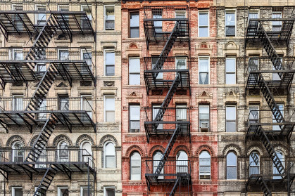 Exterior view of old New York City style architecture apartment building with windows and fire escapes