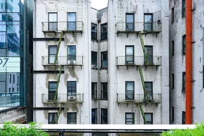 In New York City, United States this older residential building viewed from the High Line has old fashioned fire escapes visible on its exterior.