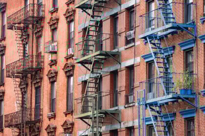 This is a photograph of brightly painted fire escapes on historic brick buildings in the Lower East Side of Manhattan.