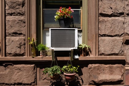 Window air conditioner with potted plants in a brick building