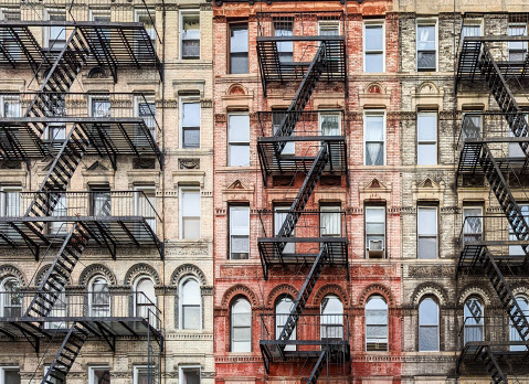 Exterior view of old New York City style architecture apartment building with windows and fire escapes