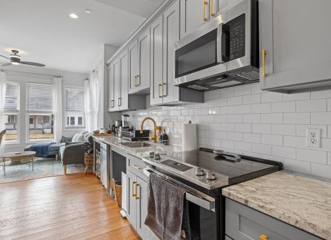 A kitchen with stainless steel appliances and counter tops and wood floor