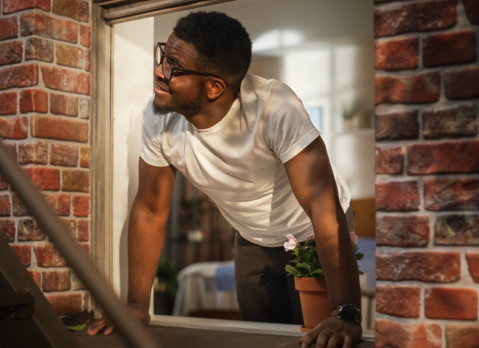 Man opening window in brick apartment building