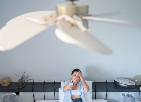 Woman using remote control for ceiling fan