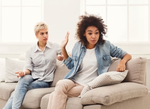 Roommates seated on a couch having an argument