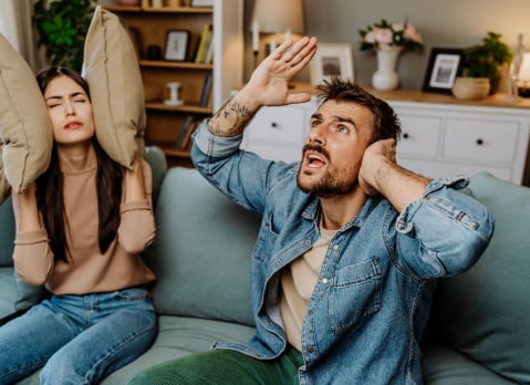Couple sitting on couch upset by loud neighbors