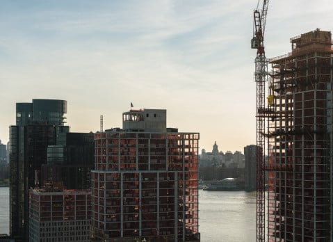 Modern buildings under construction on the waterfront in Greenpoint, Brooklyn with the view of Manhattan with Freedom Tower over the East River. Modern buildings under construction on the waterfront in Greenpoint, Brooklyn with the view of Manhattan with Freedom Tower over the East River.