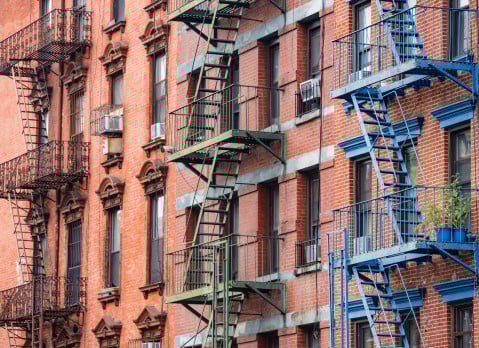 This is a photograph of brightly painted fire escapes on historic brick buildings in the Lower East Side of Manhattan.