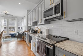 A kitchen with stainless steel appliances and counter tops and wood floor