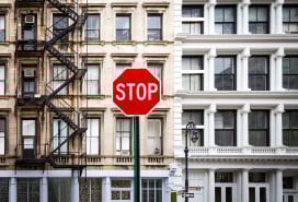A photo of a stop sign in front of an NYC apartment building.