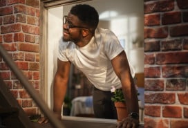 Man opening window in brick apartment building