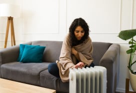young woman using space heater to supplement apartment heat