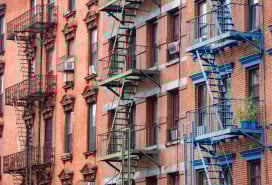 This is a photograph of brightly painted fire escapes on historic brick buildings in the Lower East Side of Manhattan.