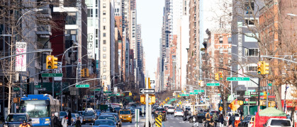 Busy intersections along 3rd Avenue are crowded with crowds of people and cars during rush hour traffic in the East Village neighborhood of Manhattan