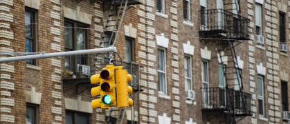 Close-up view of a traffic light and some buildings on background with windows and emergency stairs. Bronx District,