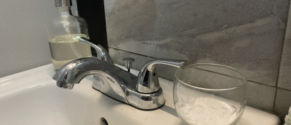 A cup of baking soda sits on a bathroom sink.