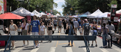 Participants walk down closed street during 7th Heaven fair in Park Slope with vendor stalls