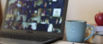 A laptop is open on a table to an online meeting.