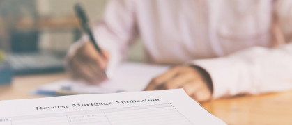 Hand fill out reverse mortgage loan application on a clipboard.