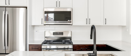 Contemporary kitchen design with white shaker style cabinets and white counters and backsplash. Small kitchen in city apartment.