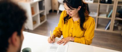 Young woman, signing a contract during an meeting with a male real estate agent