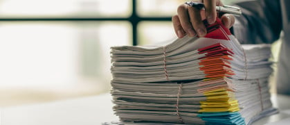 Businessman working in finance with pile of unfinished papers on the desk business paper pile stock photo