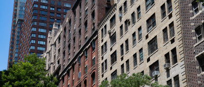 A row of old brick apartment building skyscrapers along a street on the Upper West Side of New York City