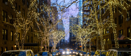 New york city street and brownstone buildings with trees covered in Christmas white lights one point perspective car dusk or early morning stock photo New york city street and brownstone buildings with trees covered in Christmas white lights one point perspective car dusk or early morning stock photo