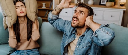 Couple sitting on couch upset by loud neighbors