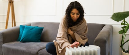young woman using space heater to supplement apartment heat