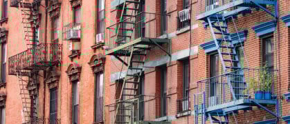This is a photograph of brightly painted fire escapes on historic brick buildings in the Lower East Side of Manhattan.