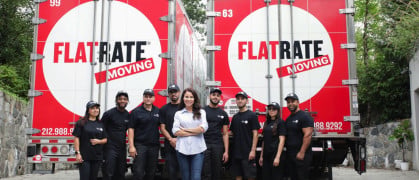 Team members and founder standing in from of two FlatRate Moving trucks