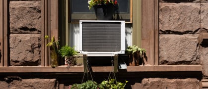 Window air conditioner with potted plants in a brick building