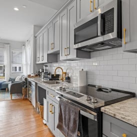 A kitchen with stainless steel appliances and counter tops and wood floor