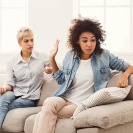 Roommates seated on a couch having an argument