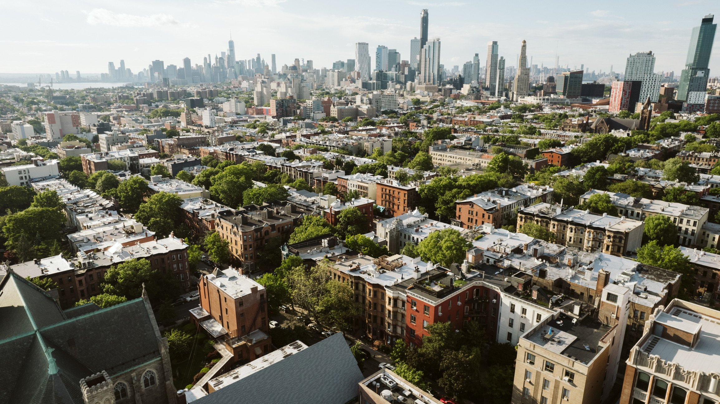 A view of short Brooklyn buildings with the Manhattan skyline in the background